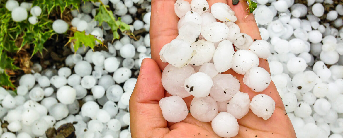 Big hailstones in the hand with hailstones in background